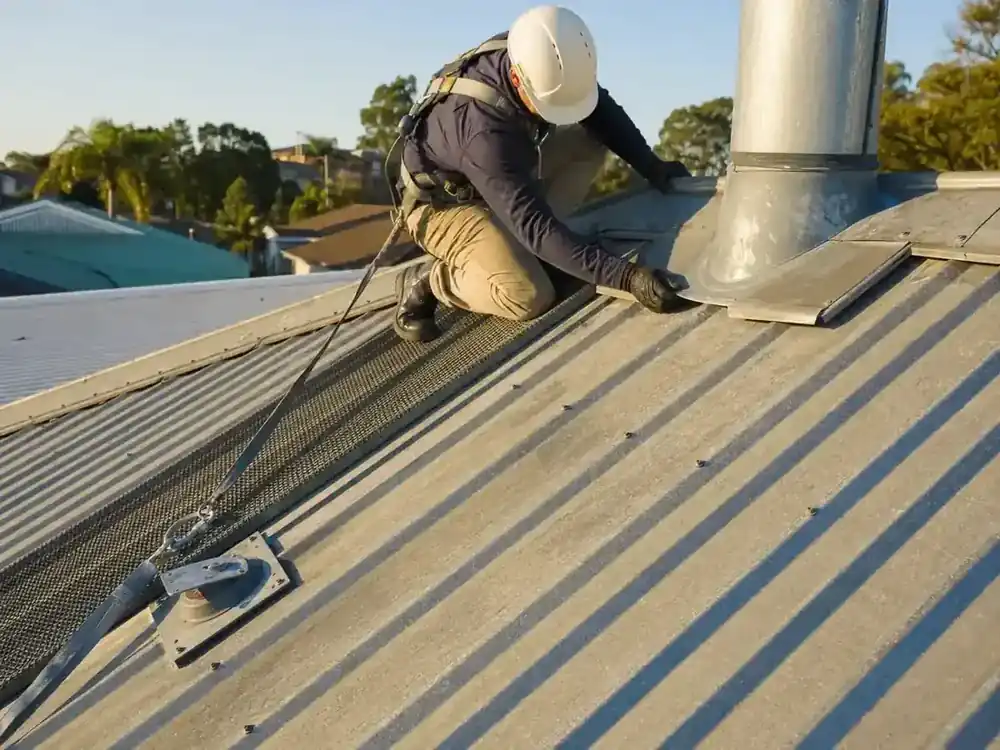 Simulated scene of a harnessed technician assessing metal-roof flashing