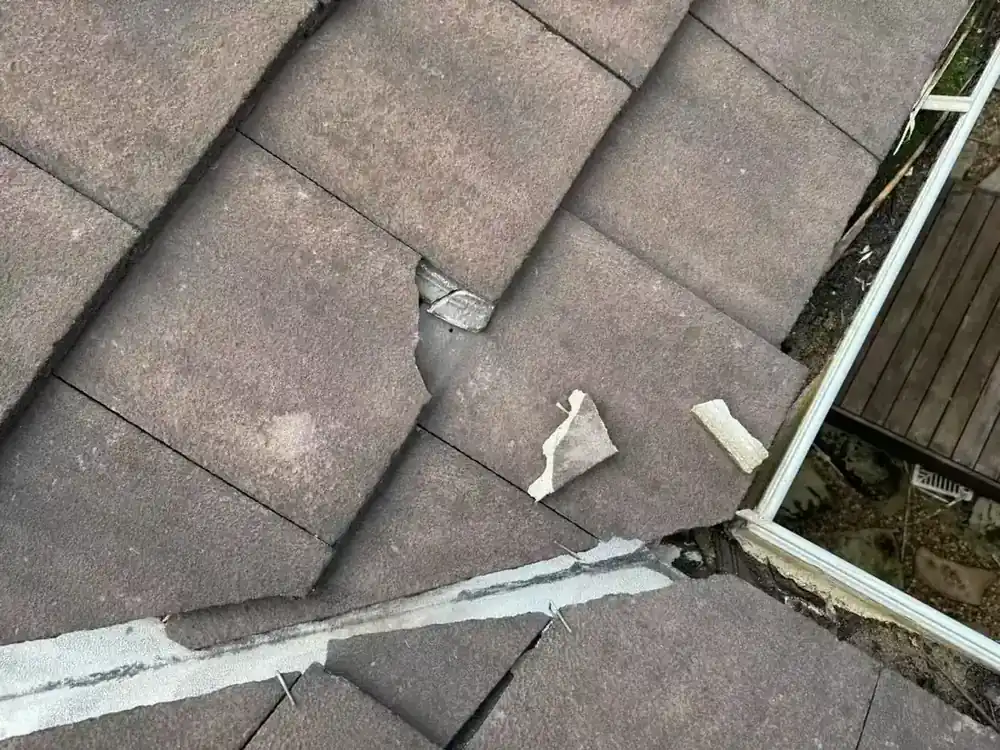 Roof photograph showing damaged tile pieces beside a gutter