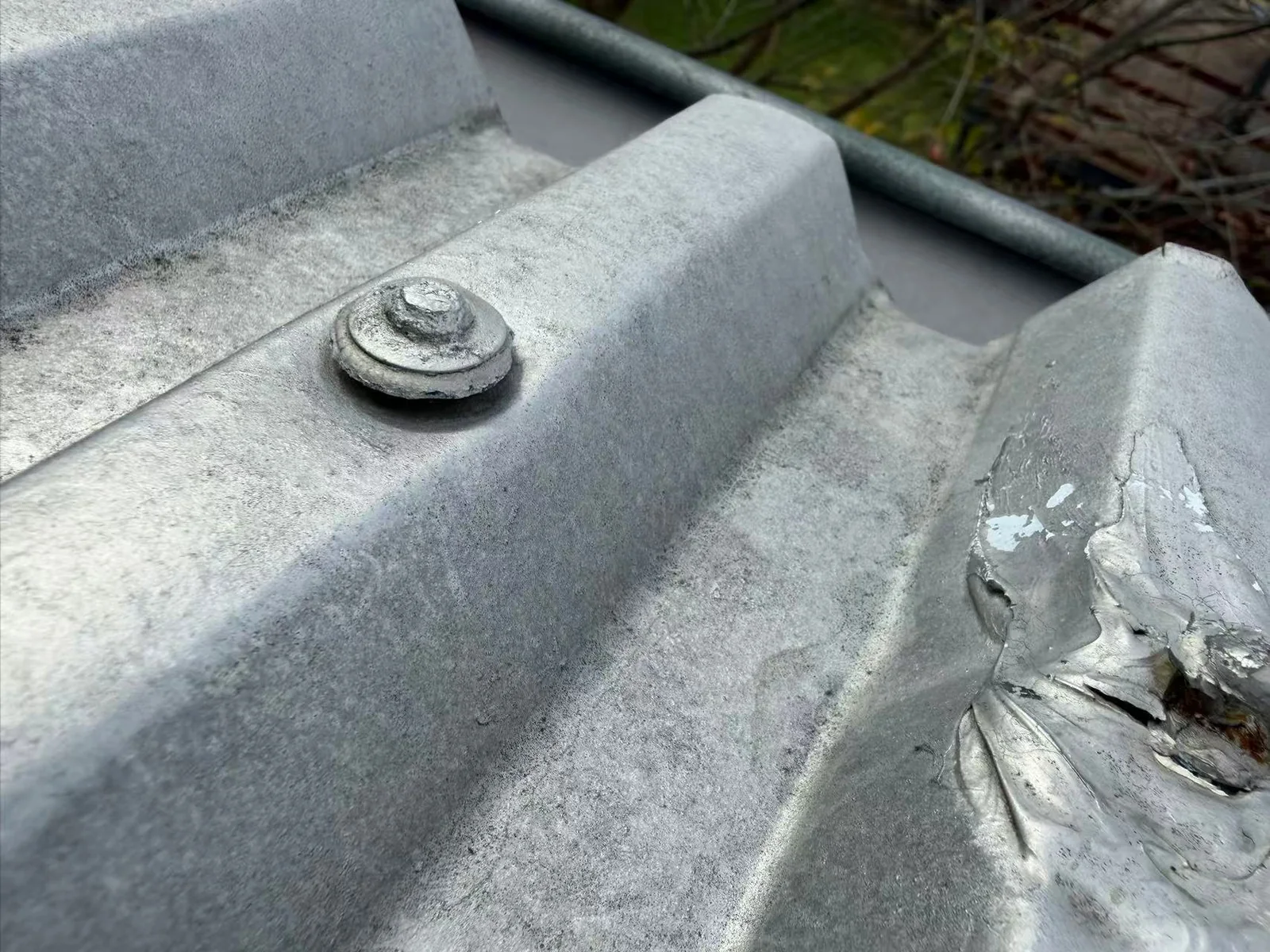 Metal roof fastener beside a sealed sheet junction